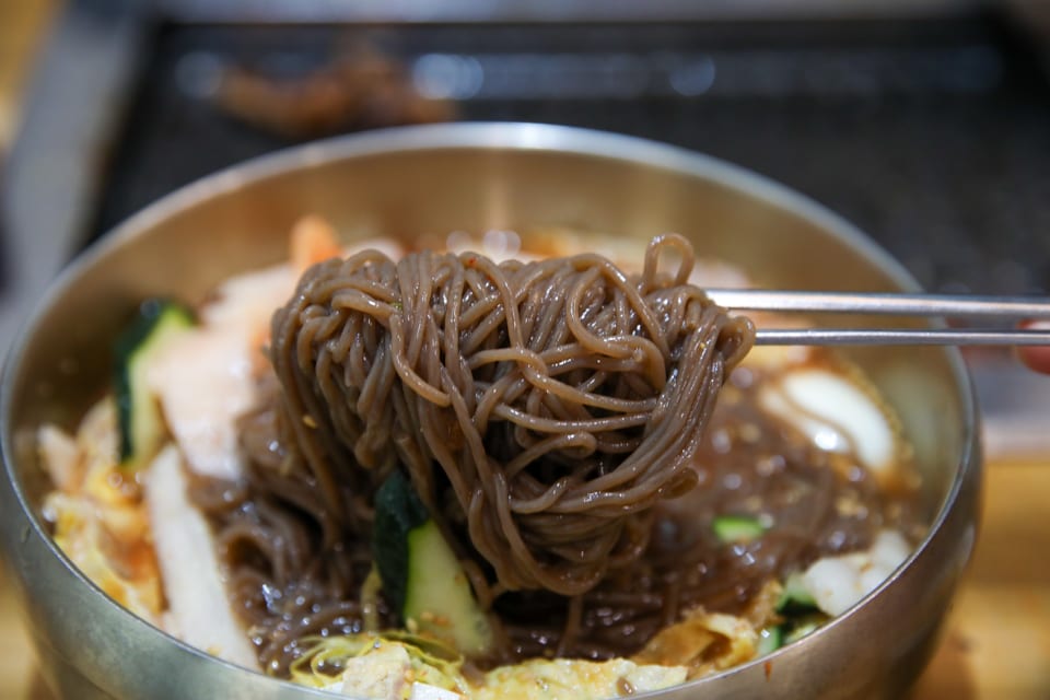 진주 얼치기 진주 물냉면 메밀순면을 드는 모습, 얼치기 뜻·성찬익수 안내
